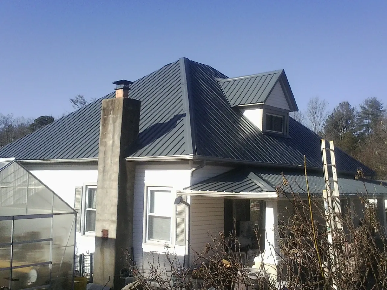 Dark blue standing seam metal roof on a white farmhouse with dormer — Slate & Tile Roof Repair by Roofing Brothers in Mccleary