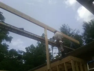 Carpenter setting a ridge beam over a new addition frame — Ice Dam Removal by Roofing Brothers in Mccleary