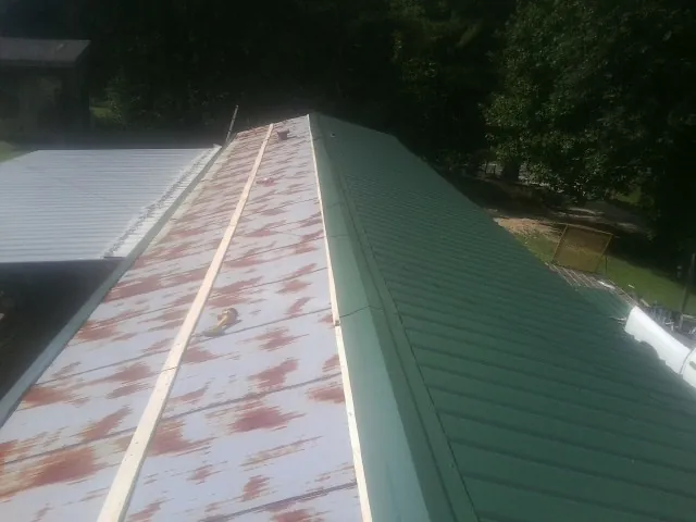 Old rusted panels beside newly installed green metal roofing — Wind Damage Roof Repair by Roofing Brothers in Mccleary