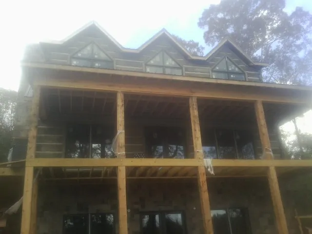 Dormers and porch framing on a large log home under construction — Roof Coating work by our crew in Mccleary