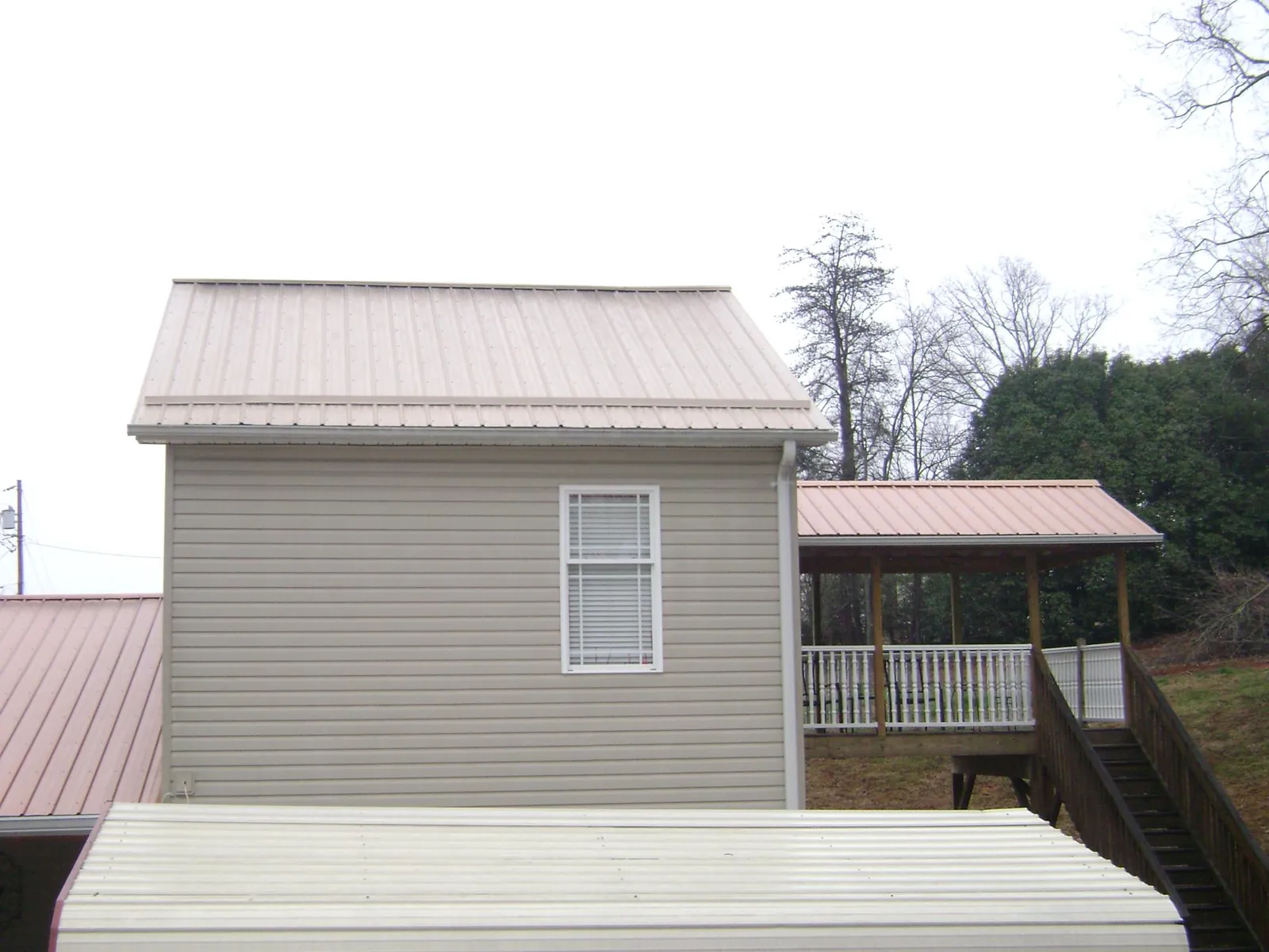 Tan metal roofs on a two story addition and attached porch, from a Roof Replacement job in Mccleary