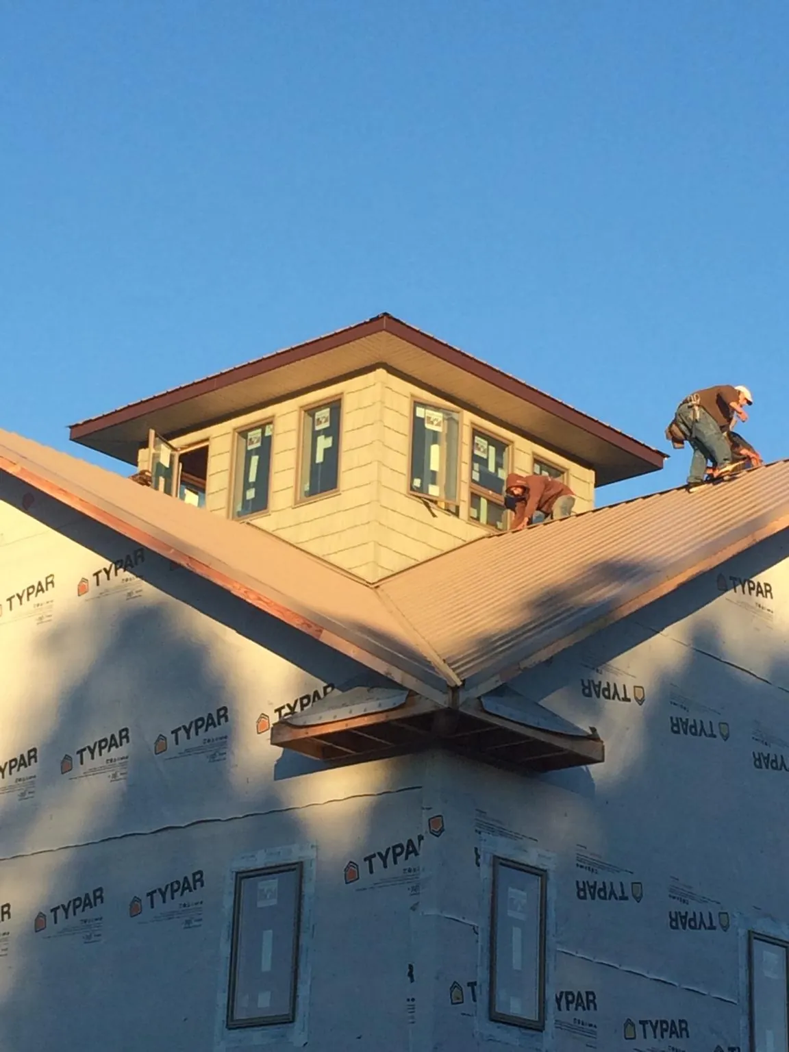 Roofers working around a rooftop cupola on a new metal roof at sunset — Roof Waterproofing in Mccleary by Roofing Brothers